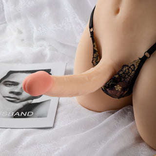 Transsexdocka i underkläder, tillverkad av silikon, ligger på en spetsunderlägg; produkten har ljusa nyanser och realistiska designdetaljer.