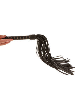 En hand tar tag i TabooM Studded Flogger med flera svarta lädersvansar mot en enkel bakgrund, som förkroppsligar essensen av BDSM-tjusning.