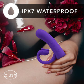 HOP - Oh Bunny - Sugande Rabbitvibrator 19 cm, tillverkad av silikonmaterial, hålls elegant bland flytande livfulla röda blommor. Denna lila klitorisstimulator har en IPX7 vattentät klassificering, perfekt för utforskning.