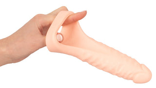 En hand håller Double Trouble Kukring, en realistisk silikonprotes i köttton, designad för mångsidig personlig användning.