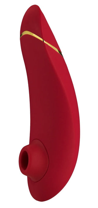 Womanizer Premium 2 är en röd, ergonomiskt utformad personlig massageapparat med en slät finish, med Pleasure Air™-teknik för en oöverträffad upplevelse, en liten öppning i ena änden och guldlinjedetaljer nära toppen.