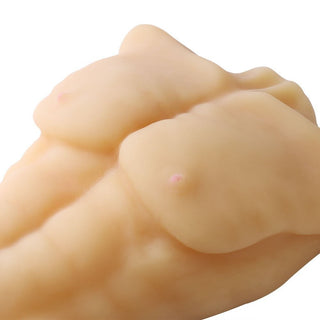 Närbild av Manlig Sexdocka, ett beige, texturerat föremål som liknar en stiliserad överkropp med definierade muskler och två små knölar.