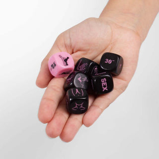 En hand håller kärlekstärningen Sextärningar, med rosa och svarta färger med suggestiva symboler och ord, mot en enkel bakgrund.