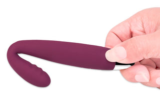 En hand håller den lila, böjda Svakom Cici vibratorn mot en vit bakgrund, vilket framhäver dess eleganta silikondesign.