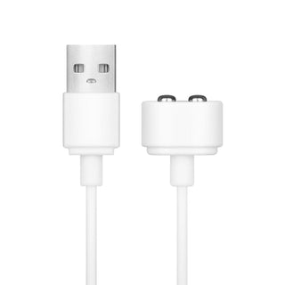 En vit USB-laddningskabel har en USB-A-kontakt och en magnetliknande kontakt med två pogo-stift, perfekt för att driva enheter som Teazers Dildo med klitorisstimulator, mot en ren, vit bakgrund.