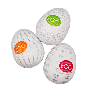 Set med tre vita Twister Egg Runkägg-behållare i plast med olika mönster och färgglada tryckta etiketter.