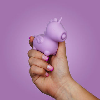 En hand håller Unihorn Karma Vibrator i lila, gjord av kroppssäker silikon, mot en matchande lila bakgrund.
