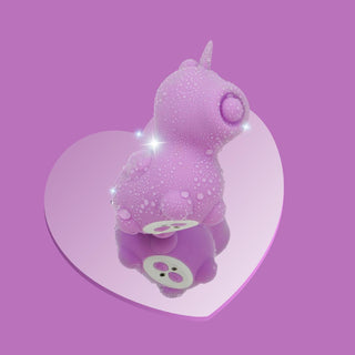 En lila Unihorn Karma Vibrator, tillverkad av kroppssäker silikon, står elegant på en hjärtformad spegel med vattendroppar mot en lugnande lila bakgrund.