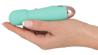 En hand håller Cuties Mini Wand - 12 cm, en liten blågrön vibrator med räfflade detaljer och en metallisk spets. Tillverkad av silikon för nöje och hållbarhet, är denna diskreta enhet perfekt för intim användning.