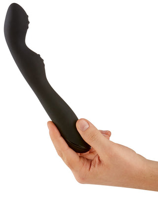 En hand håller Rebel Prostata Vibrator - P-Spot 23,5 cm, en elegant, svart, böjd silikonenhet, mot en vit bakgrund.
